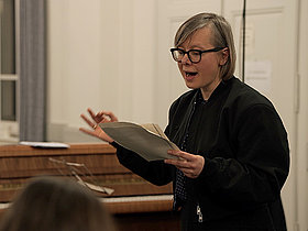 Frau mit Noten in der hand vor Klavier, Deutscher Musikrat, Podium Gegenwart