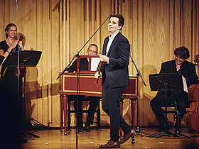 Flötist MAx Volers auf der Bühne mit seiner Flöte in der HAnd, stehend vor Mitmusizierenden, Deutscher Musikwettbewerb, Deutscher Musikrat