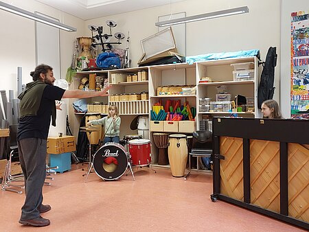 Mann und Kinder im Musikunterricht an Instrumenten