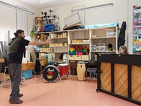 Mann und Kinder im Musikunterricht an Instrumenten