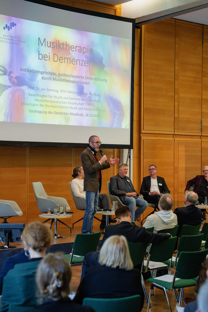 © Dominique Krentscher Prof. Dr. Jan Sonntag präsentiert auf der Bühne der DMR Fachtagung Musik und Gesundheit 2024