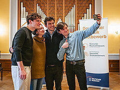 4 Personen in einem Saal stehend ein Selfie machend, Preisträger Deutscher Musikwettbewerb 2025