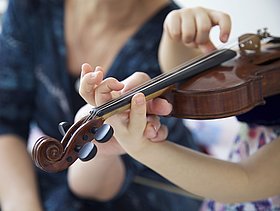 Eine Frau unterrichtet ein junges Mädchen an der Violine