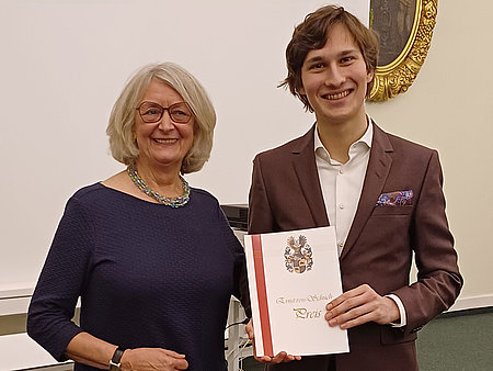 Preisträger Aurel Dawidiuk mit Urkunde in der Hand neben Martina Damm.