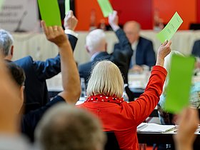 Wahlzettel werden bei einer Versammlung in die Luft gehalten