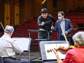 Dirigenten auf der Bühne vor Orchester, Dominik Beykirch mit Hankyeol Yoon im Dirigierkurs „Zurück ans Pult“