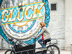 Ulrike Eickenbusch, Cellistin im Stuttgarter Kammerorchester auf einem LAstenrad. Thema Klimaschutz. Deutsches Musikinformationszentrum