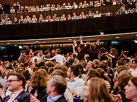 Publikum in einem Saal sitzend