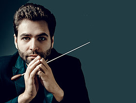 Portraitfoto von Dirigent Simon Edelmann mit Dirigierstab, Deutscher Musikrat, Forum Dirigieren