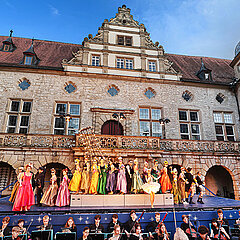Musikerinnen und Musiker und Chormitglieder auf der Freilichtbühne vor Schloss Weikersheim spielend